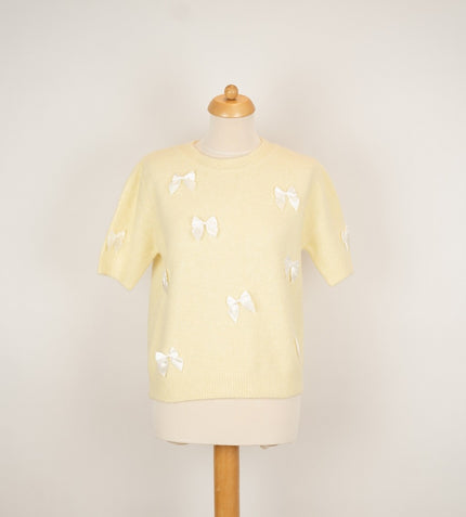 Zachtgeel truitje met witte strikken