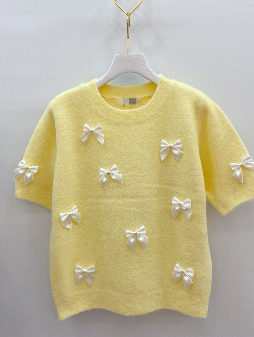 Zachtgeel truitje met witte strikken